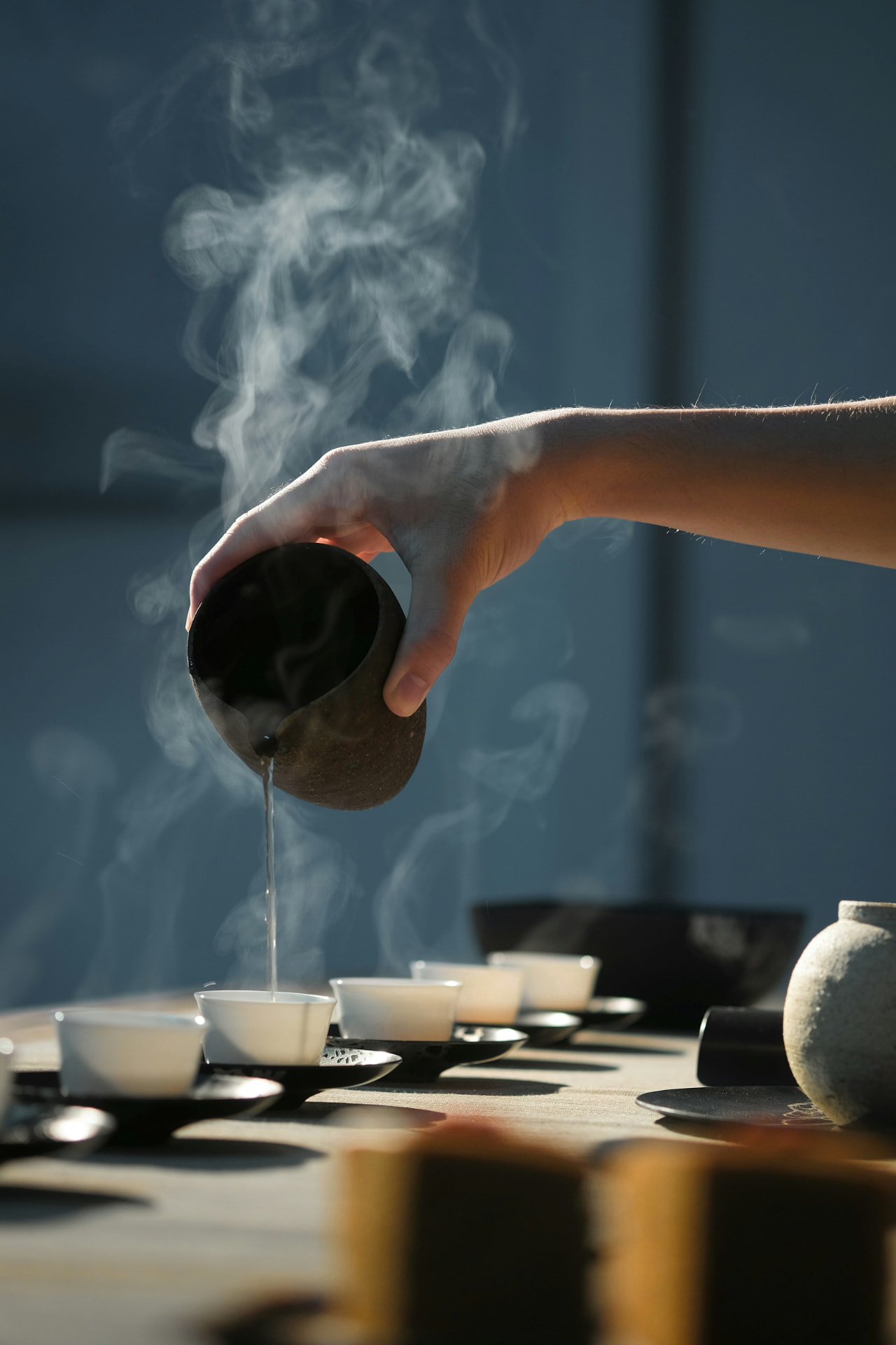 Hands pouring tea, steam rising in low light